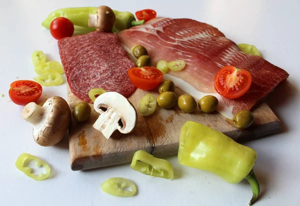Gıda - ahşap kesme tahtası üzerinde mantar, zeytin ve sebze (domates ve yeşil biber ile düzenlenmiş et ürünleri (jambon füme ve salam))