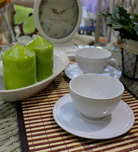 杯子放在桌子上 桌上放着老式时钟和绿色装饰蜡烛 — 图库照片