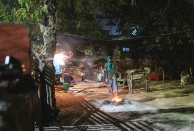 Bir adam ateşin yanında ayaklarını ısıtır.. 
