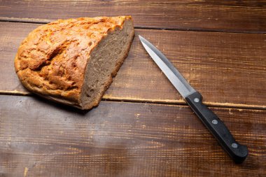 Kahverengi bir masa ve bıçak üzerinde taze bir çiftlik (sözde ekmek).