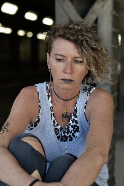 a stressed mature punk woman is looking thoughtful down