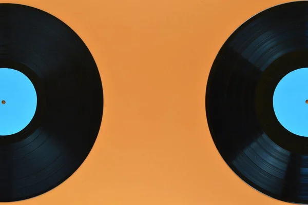 两个旧的黑色乙烯基唱片 空白青色标签一半在橙色背景 — 图库照片