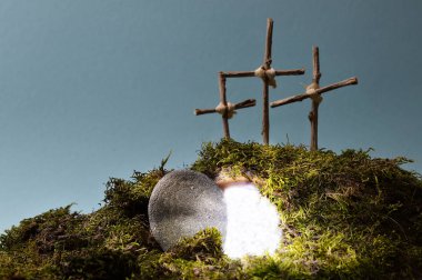 resurrection garden as easter decoration with a stone near the empty tomb filled with blinding light and three crosses on a hill above