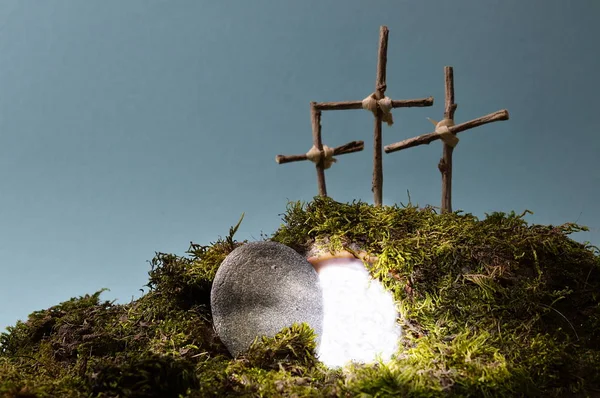 复活庭院作为复活节装饰用石头在空的坟墓附近充满刺眼的光和三十字架在一座山上面 — 图库照片