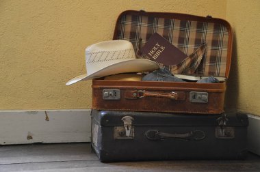 Suitcase filled with clothes, hat and a bible for a mission journey clipart