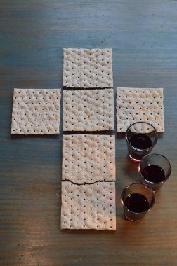 The Lord's Supper with bread in the shape of a cross and three little cups of wine clipart