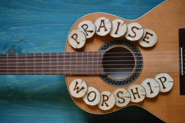 Bu kelime yazı üzerinde ahşap parçaları ile deniz mavisi ahşap arka plan üzerinde gitar: övgü ve ibadet