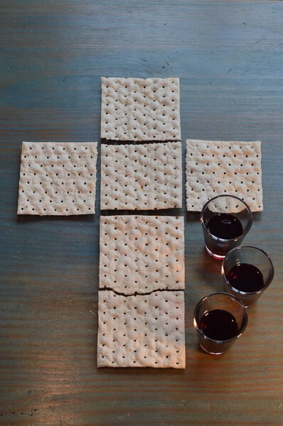 The Lord's Supper with bread in the shape of a cross and three little cups of wine