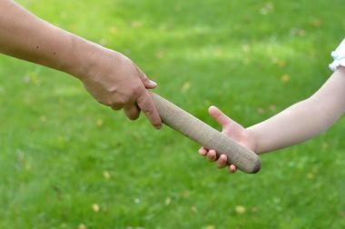 woman giving the relay baton to the next generation into a child's hand clipart