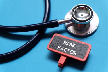 Seçici odak stetoskop ve yazı tahtası 'Risk faktörü' ile mavi arka plan üzerinde yazılı. Sağlık ve tıp kavramı.