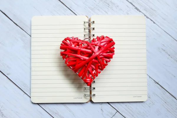 白い木製の背景に開いた本の赤い木製手芸ハートマークの上から見る バレンタインの日のテーマ — ストック写真