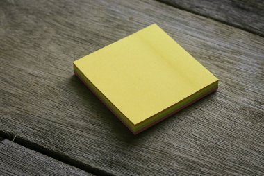 Ahşap arkaplanda boş sarı yapışkan notlar.