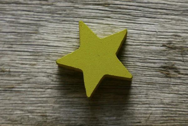 Žlutá dřevěná hvězda tvar na dřevěném pozadí. — Stock fotografie