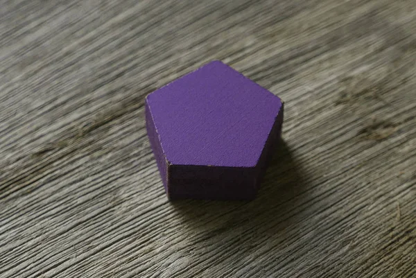 Fioletowy kolor drewniany pentagon kształt na drewnianym tle. — Zdjęcie stockowe