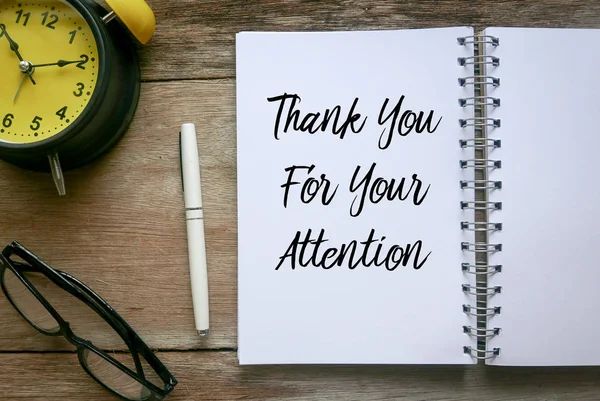 Top view of clock,glasses,pen and notebook written with Thank You For Your Attention on wooden background. — Stock Photo, Image