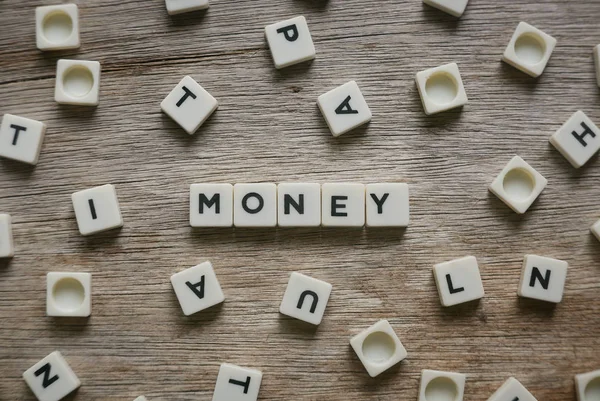 Money in alphabet on wooden background. — Stock Photo, Image