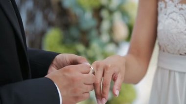 Gelin ve damat nikah yüzükleri çiçek kompozisyon çerçevede bir değiş tokuş. Damat yüzük onun gelin yakın çekim kolunda koyar. Düğün günü.