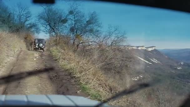 Conduciendo jeeps todoterreno anticuados. Imágenes suaves de un vehículo todoterreno que va cuesta arriba al borde de un acantilado. Turismo automovilístico extremo. Vista de las montañas desde un coche todoterreno . — Vídeos de Stock