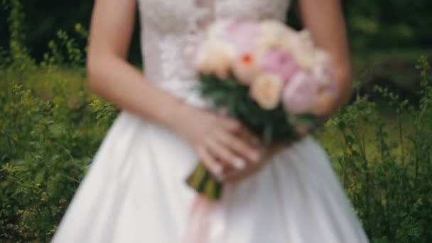 Bruden håller en bröllop bukett av rosor och pioner. Brudbukett bröllop dag. Bukett av olika blommor. Bukett med vackra rosa, creme och vita blommor — Stockvideo