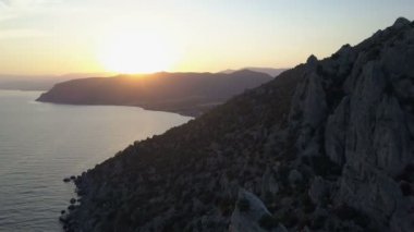 Kayalar ve gün batımına doğru deniz üzerinde uçuş.