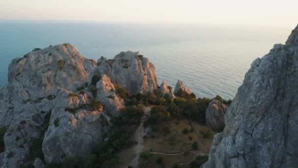 Vol de drone entre les rochers au coucher du soleil face à la mer . — Video