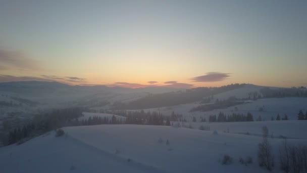 Vuelo aéreo del paisaje invernal nórdico sobre el bosque montañoso de nieve al amanecer. Vuelo de drones de invierno sobre montañas a través de una niebla . — Vídeo de stock