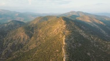 Hava güzel dağlar yeşil orman tarafından örtülü bir kadeh. Uçuş günbatımı dağda bir sırt boyunca. Ufukta bulutlar.