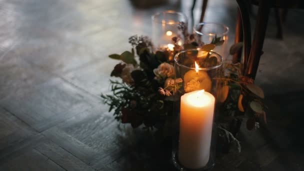 Αναμμένα κεριά με όμορφο μπουκέτο από διαφορετικά λουλούδια κοντά σε μια καρέκλα. — Αρχείο Βίντεο