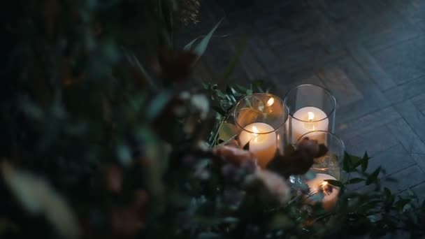 在镶木地板上用不同花朵的美丽花束燃烧蜡烛. — 图库视频影像
