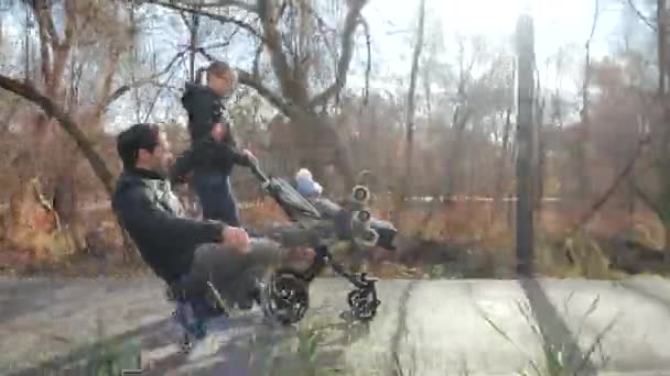 En promenad i höstparken rullskridskoåkning med ett barn. Sakta i backarna. Pappa kör på ett hjul och underhåller barnet. Ljus, solig dag. Idrottsutbildning och hälsosam passion. — Stockvideo