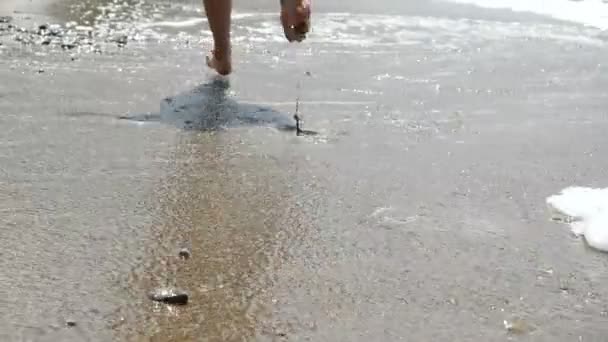 Крупным планом женские ноги бегают по жаркому солнечному песчаному пляжу. Активная спортивная босиком женщина бегает по песку вдоль побережья в медленном движении. Фитнес, бег трусцой и спортивная активность — стоковое видео