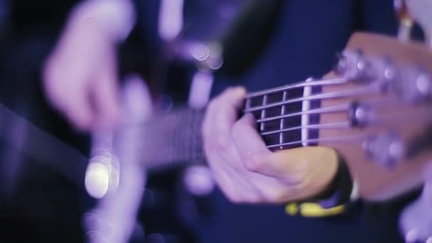 Professional young bass player playing guitar solo. A close up view of the hands of a bass guitar and a rock guitarist. The musician performs at a concert and plays the instrument well. — Stockvideo