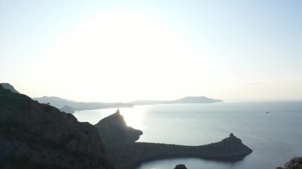 Luftbild einer jungen Frau, die bei Sonnenaufgang auf einem Berg über dem Meer steht. Seitenflug einer jungen aktiven Frau auf den Gipfel der Krim mit ausgestreckten Armen. Bergsteigerin — Stockvideo