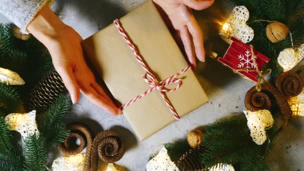 De vrouw geeft haar man een kerstcadeau, legt het op tafel, en dan pakt de man het op. Het gezin wisselt geschenken uit tijdens de wintervakantie. Gelukkig Nieuwjaar en Kerstmis. Bovenaanzicht. — Stockvideo