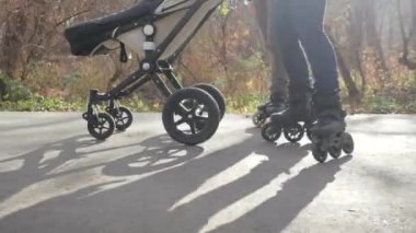 Sıcak ve güneşli bir sonbaharda bir aile, çocuklarıyla bebek arabasında paten kayar. Aşağı görünüm Yavaş hareket.