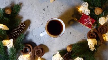Yeni yıl masasında bir fincan siyah çay ya da kahve, erkekler tarafından çekiliyor. Masada Noel ve yeni yıl süslemeleri, çam ve ladin dalları, koniler, fındıklar, çelenkler. Görünümün üstünde.