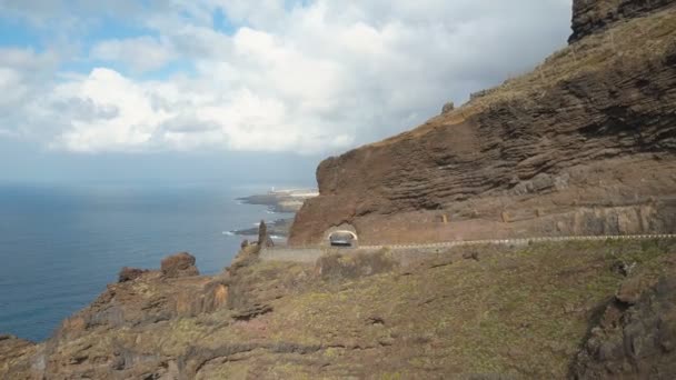 Αεροφωτογραφία απότομων βράχων πάνω από τον Ατλαντικό Ωκεανό. Ορεινοί δρόμοι και τούνελ σε ένα βράχο. Πτήση προς τα πίσω πάνω από το κατάστρωμα παρατήρησης Punta del Fraile, Τενερίφη, Κανάριοι Νήσοι, Ισπανία. — Αρχείο Βίντεο