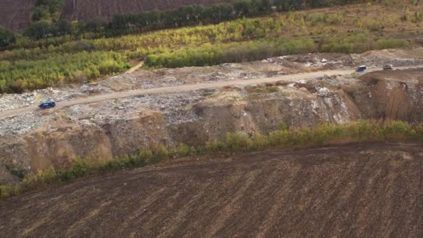 Vrachtwagens brengen afval naar een vuilnisbelt in de vuilnisbelt. Luchtfoto van grote vuilnishoop op de sorteerplaats. Milieuvervuiling door consumentisme. Afvalverwerking op een vuilnisbelt. — Stockvideo