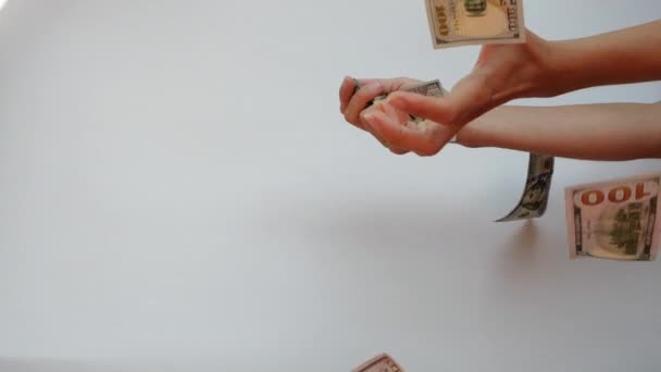 Womans hands catch two 100 US Dollar banknotes falling in slow motion against white background. — Stock Video