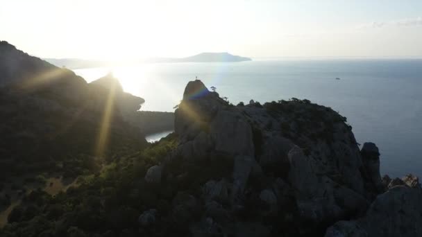 Vzdušná silueta mladé ženy zvedající ruce na vrcholku hory nad mořem za úsvitu. Mladá aktivní žena na vrcholu hory na Krymu. Lady Mountaineer na vrcholu — Stock video