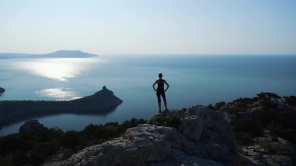 Donna escursionista in montagna su un mare godendo di una splendida vista e la natura selvaggia circostante all'alba. Vittoria e successo, il raggiungimento dell'obiettivo. Crimea, Sudak . — Video Stock