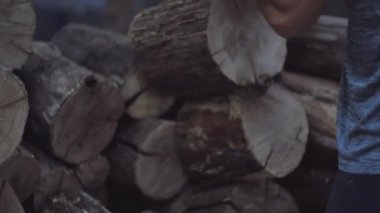 Erkek eller, meşe odunlarını kış depolarında saklamak için hazırlar. Adam odun parçalarını alır ve fırlatır..