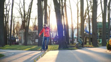 Mükemmel binicilik teknikleri ve iyi esneme teknikleriyle profesyonel bir patenci, serin bir sonbahar parkında antrenman yapmak için koni etrafında zor dönüşler yapar. Ağır çekimde alt görüntü. Sağlıklı yaşam.