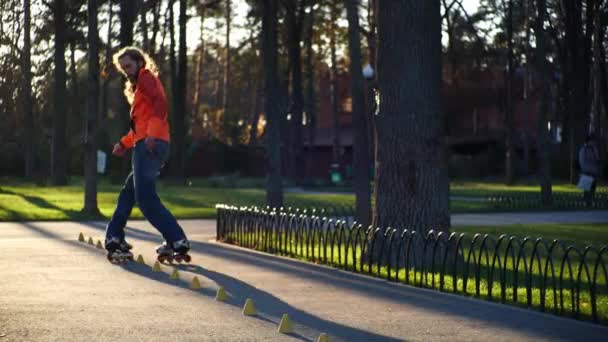 A professional male roller rides great backwards, crossing his legs and riding between the cones, then stands on two rear wheels. A man performs a technical roller skate ride in slow motion. — Stock Video