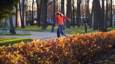 Sportif ve kullanışlı paten. Profesyonel bir adam patenle antrenman yapar, koniler arasında gezer ve sonbaharın son günlerinde şehir parkında kompleks dönüşler yapar. Yavaş çekim.