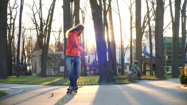 Rolki to ulubione hobby. Profesjonalny rolkarz mistrzowsko wykonuje trudną jazdę po chodniku parku miejskiego w słoneczny jesienny dzień. Oddolne ujęcia w zwolnionym tempie. — Wideo stockowe