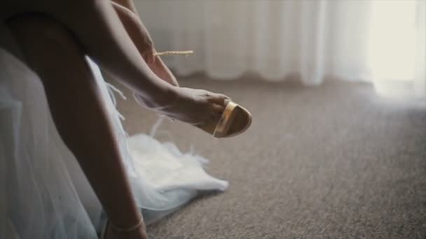 La novia lleva sus zapatos de boda. Mañana de bodas. Primer plano elegantes sandalias de mujer en una pierna delgada niñas . — Vídeos de Stock