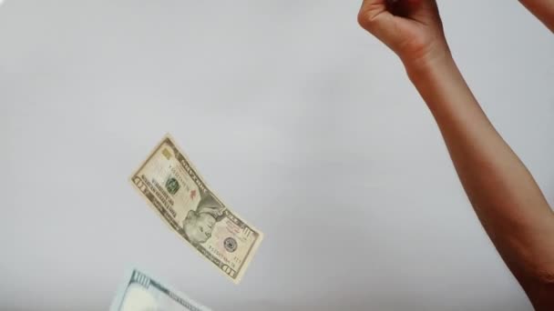 女性の手は、白い背景に対してスローモーションで落ちる米ドル紙幣の落下をキャッチしようとします. — ストック動画