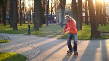 Profesyonel bir patenci, antrenman konileri ve bacak bacak bacak üstüne atarak geri geri gider. Şehrin Central Park 'ında aktif ve sportif bir eğlence. Ağır çekimde aşağıdan çekim.