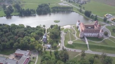 Beyaz Rusya 'daki Mir Castle' ın hava görüntüsü. Sonbaharda Güzel Mir Kalesi 'nin kuş bakışı manzarası. İHA 'dan ateş etmek. Bir göl ve ağaçlar arasında tarihi bir dönüm noktası. Üst görünüm yavaş çekimde.